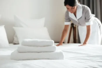 Well trained maid making a bed at a hotel. Keeping an eye out for signs of bed bugs.