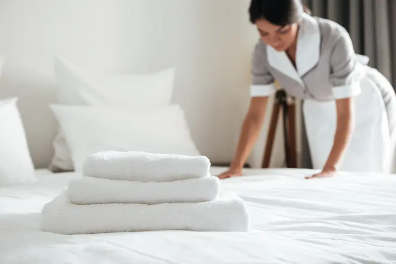 Well trained maid making a bed at a hotel. Keeping an eye out for signs of bed bugs.