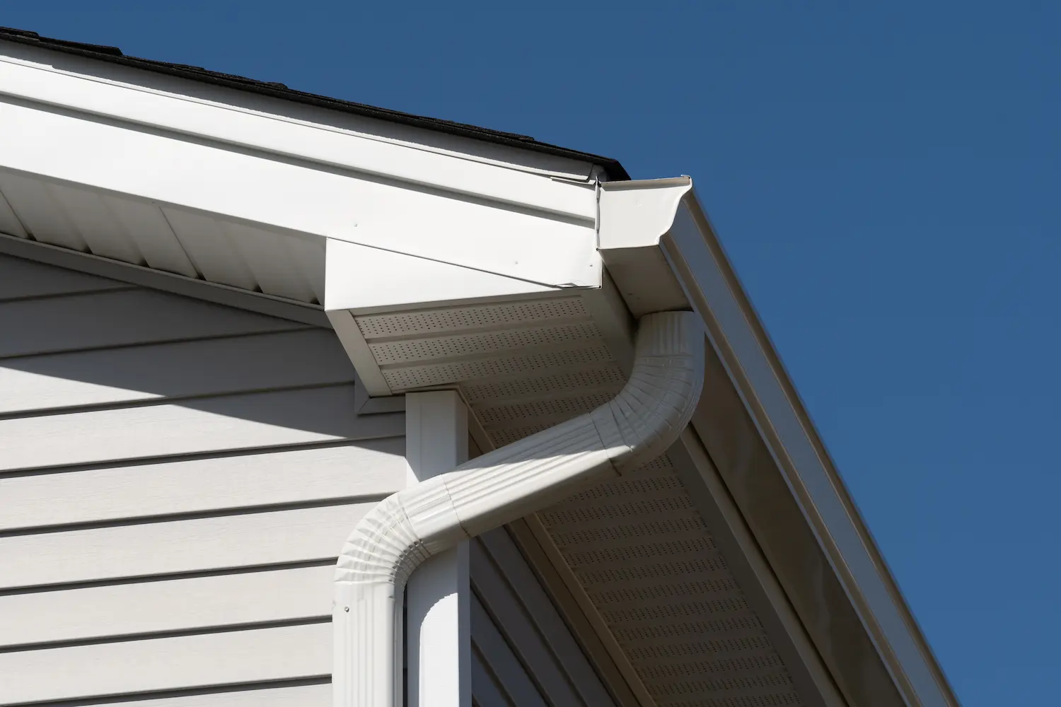 A close up of the corner of a residential homes gutter and and downspout.