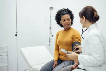 Female doctor and female patient in a doctors office and the doctor is taking the patients blood pressure